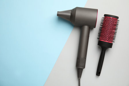Hair dryer and round brush on color background, flat lay. Space for textの写真素材