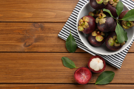 Fresh ripe mangosteen fruits on wooden table, flat lay. Space for textの写真素材