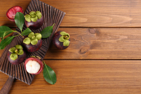 Fresh ripe mangosteen fruits on wooden table, flat lay. Space for textの写真素材