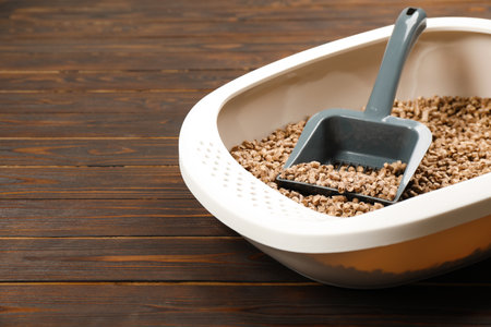 Cat litter tray with filler and scoop on wooden background, closeup. Space for textの写真素材