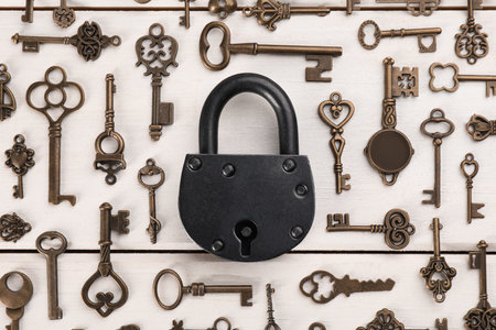Flat lay composition with padlock and beautiful vintage keys on white wooden tableの写真素材