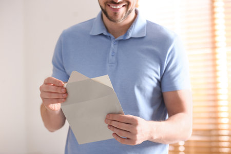 Man holding envelope with blank greeting card indoors. closeupの写真素材