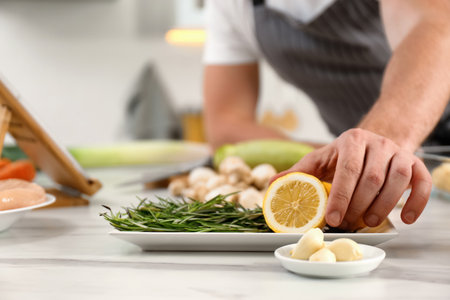 Man making dinner while watching online cooking course via tablet kitchen, closeupの写真素材