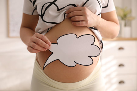 Pregnant woman with empty paper thought cloud indoors, closeup. Choosing baby nameの写真素材