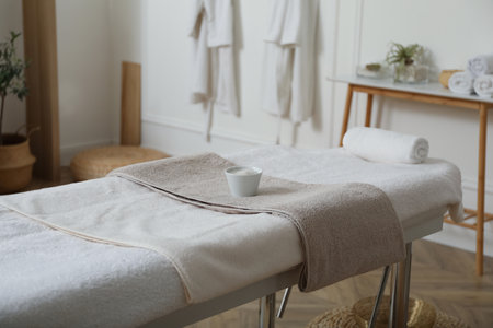 Sea salt for spa procedure and soft terry towels on massage table in salonの写真素材