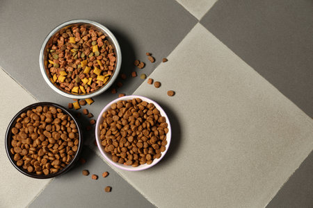 Pet bowls with dry food on floor, flat lay. Space for textの写真素材