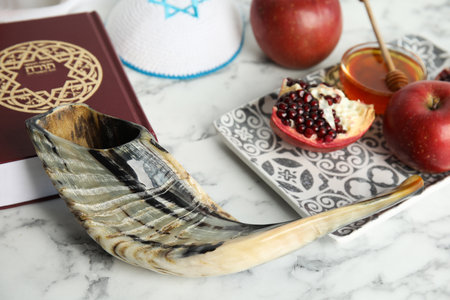 Shofar, kippah and book Torah with text in Hebrew on white marble table, closeup. Rosh Hashanah celebrationの写真素材