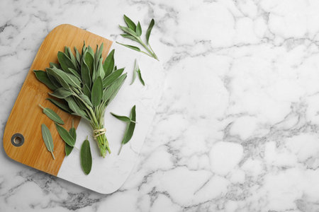 Board with fresh green sage on white marble table, flat lay. Space for textの写真素材