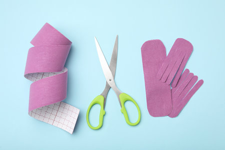 Bright kinesio tape pieces and scissors on light blue background, flat layの写真素材