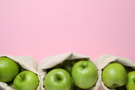 Sacks with ripe green apples on pink background, flat lay. Space for textの写真素材