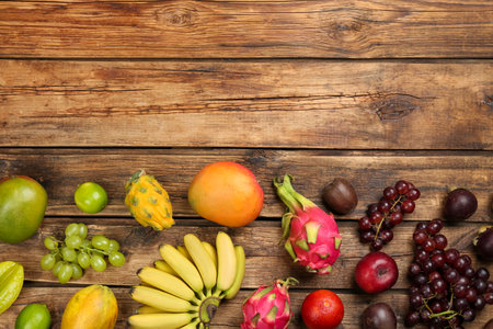 Many different delicious exotic fruits on wooden table, flat lay. Space for textの写真素材
