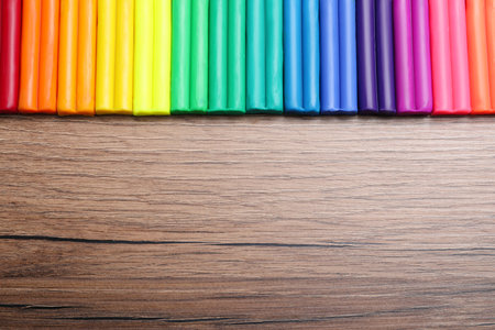 Many different colorful plasticine on wooden table, flat lay. Space for textの写真素材