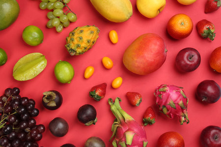 Many different delicious exotic fruits on red background, flat layの写真素材