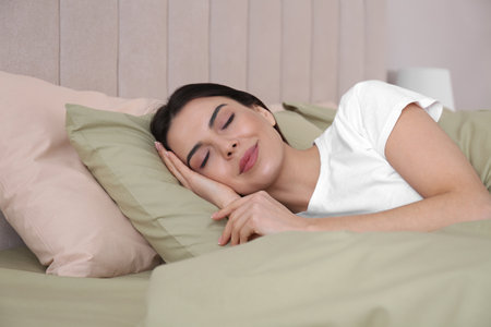 Woman sleeping in comfortable bed with green linensの写真素材