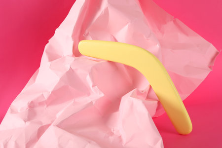 Creative composition with yellow wooden boomerang on pink backgroundの写真素材