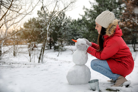Young woman making snowman outdoors on winter day. Space for textの写真素材