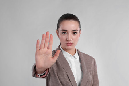 Woman in suit showing gesture stop on light grey backgroundの写真素材