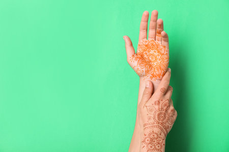 Woman with henna tattoos on hands against green background, closeup and space for text. traditional mehndi ornamentの写真素材