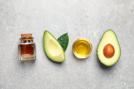Flat lay composition with essential oil and avocado on light gray table