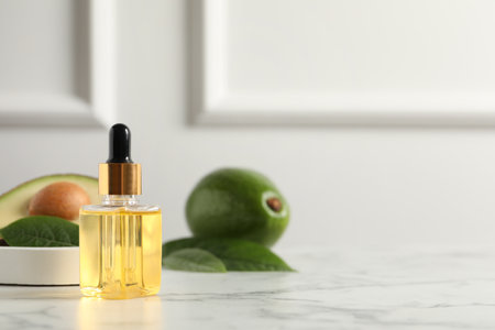 Bottle of essential oil and avocados on white marble table, space for textの写真素材