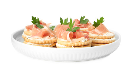 Delicious crackers with cream cheese, prosciutto and parsley on white backgroundの写真素材