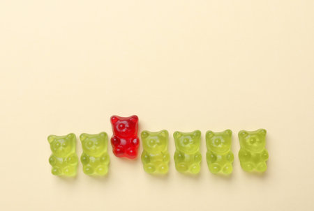 Red jelly bear among green ones on beige background, flat lay. uniqueness conceptの写真素材