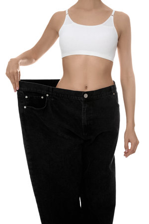 Young woman wearing big jeans after weight loss on white background, closeupの写真素材