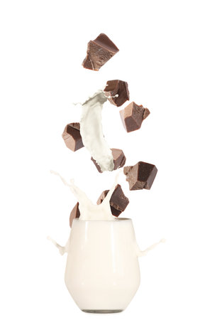 Chocolate falling into glass with milk on white backgroundの写真素材
