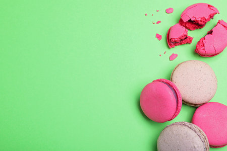 Delicious colorful macarons on green background, flat lay. Space for textの写真素材