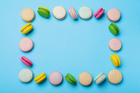 Frame made of delicious colorful macarons on light blue background, flat lay. Space for textの写真素材