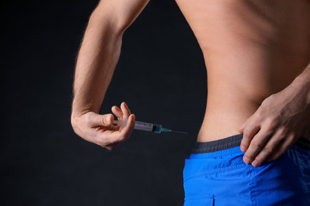 Man injecting himself on black background, closeup. Doping conceptの写真素材