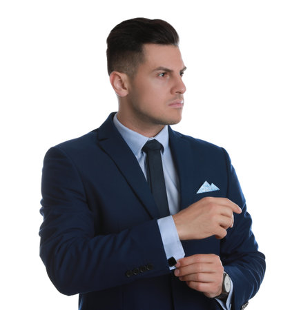 Handsome stylish man putting on cufflink against white backgroundの写真素材