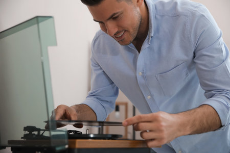 Happy man listening to music with turntable at homeの写真素材