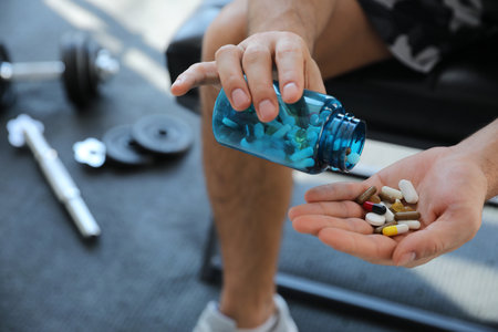 Sportsman with bottle of pills in gym, closeup. Doping conceptの写真素材