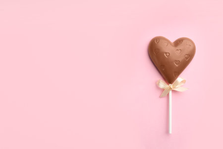 Chocolate heart shaped lollipop on light pink background, top view. Space for textの写真素材