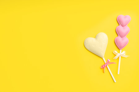 Different chocolate heart shaped lollipops on yellow background, flat lay. Space for textの写真素材
