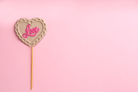Chocolate heart shaped lollipop with word Love on light pink background, top view. Space for textの写真素材