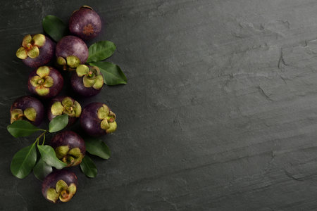 Fresh ripe mangosteen fruits on dark gray table, flat lay. Space for textの写真素材