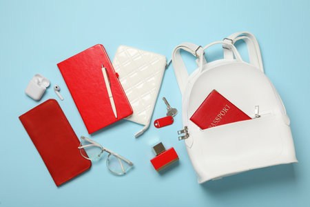 Stylish urban backpack with different items on light blue background, flat layの写真素材