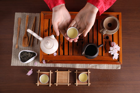 Woman with cup of freshly brewed beverage during traditional tea ceremony at wooden table, top viewの写真素材
