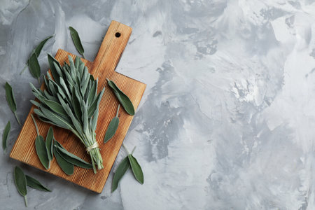Wooden board with fresh green sage on gray table, flat lay. Space for textの写真素材