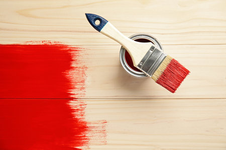 Brush and can of red dye on freshly painted wooden surface, top view. Space for textの写真素材