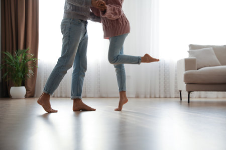 Couple dancing barefoot in living room, closeup. floor heating systemの写真素材