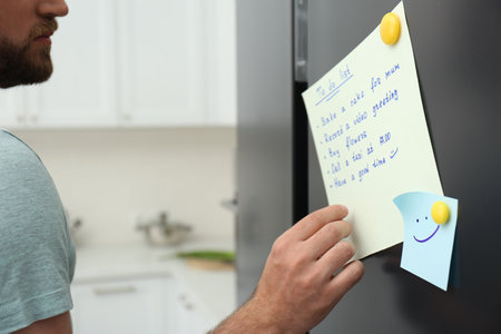 Man checking to do list on fridge in kitchen, closeupの写真素材