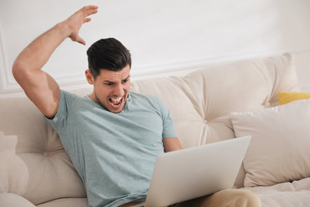 Emotional man working with laptop at homeの写真素材