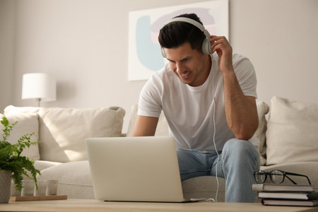 Man with laptop and headphones at table indoorsの写真素材