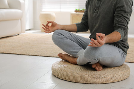 Man meditating on wicker mat at home, closeupの写真素材