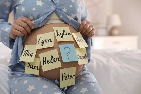 Pregnant woman with different baby names on belly in bedroom, closeupの写真素材