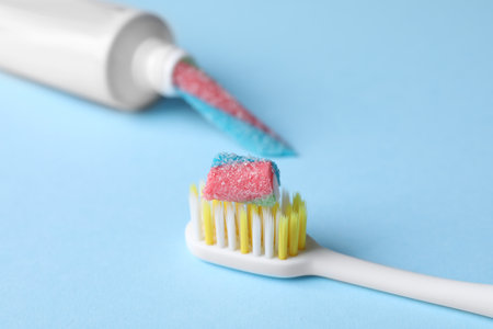 Toothbrush and tube with gummy candies on light blue background, closeup. Dangers of sugarの写真素材