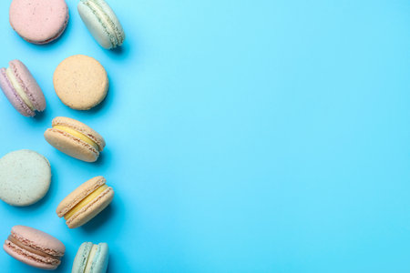 Delicious colorful macarons on light blue background, flat lay. Space for textの写真素材